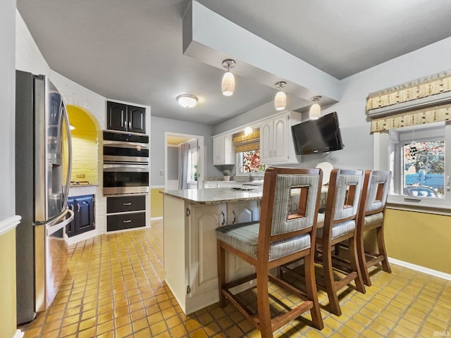 kitchen featuring appliances with stainless steel finishes, kitchen peninsula, white cabinetry, and plenty of natural light