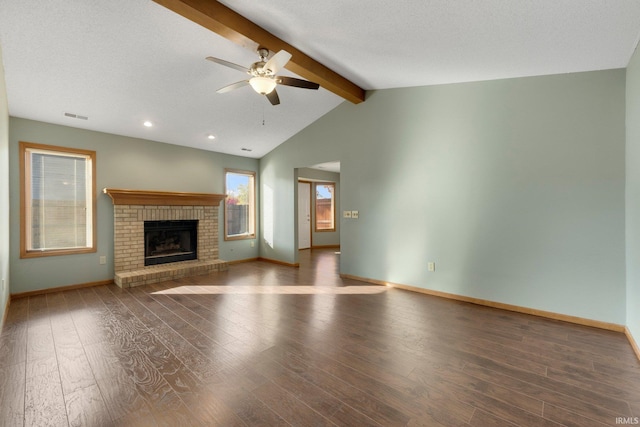 unfurnished living room with vaulted ceiling with beams, a textured ceiling, a brick fireplace, ceiling fan, and dark wood-type flooring