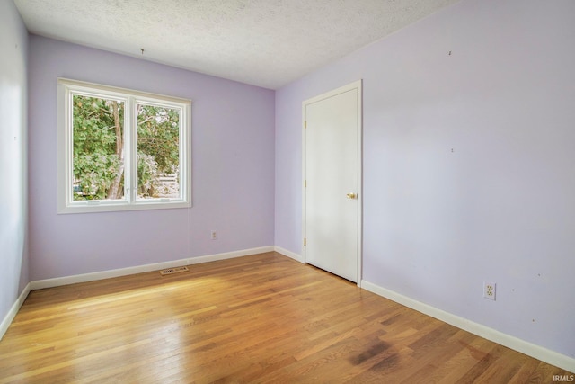 unfurnished room featuring a textured ceiling and light wood-type flooring