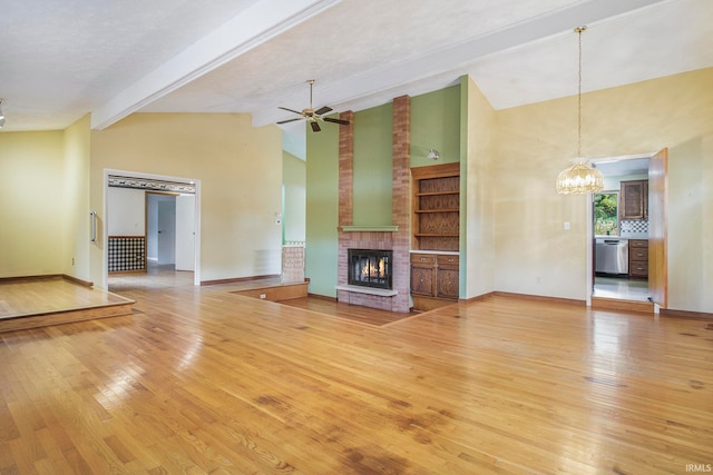 unfurnished living room with wood-type flooring, vaulted ceiling with beams, ceiling fan with notable chandelier, a textured ceiling, and a brick fireplace