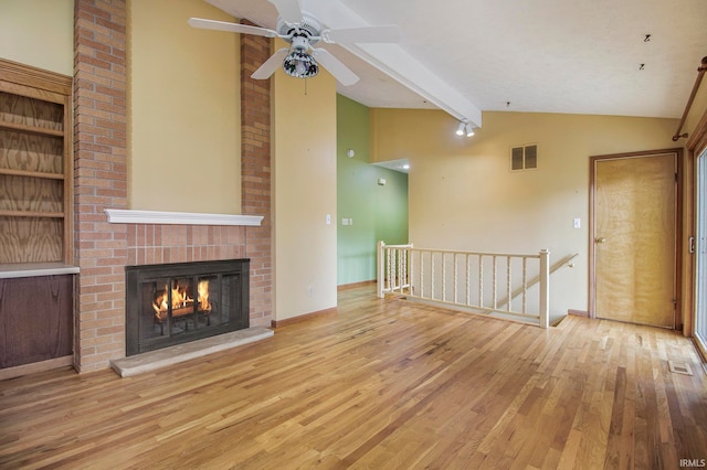 unfurnished living room with beam ceiling, light hardwood / wood-style flooring, a fireplace, and high vaulted ceiling