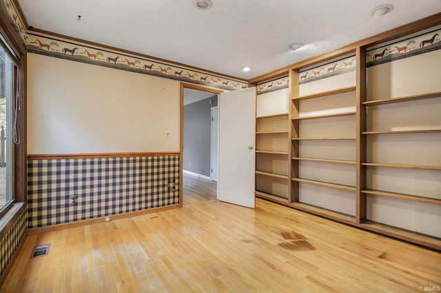 unfurnished room featuring ornamental molding, a textured ceiling, and wood-type flooring