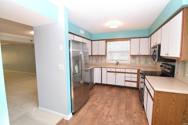 kitchen featuring sink, appliances with stainless steel finishes, light hardwood / wood-style flooring, and white cabinetry