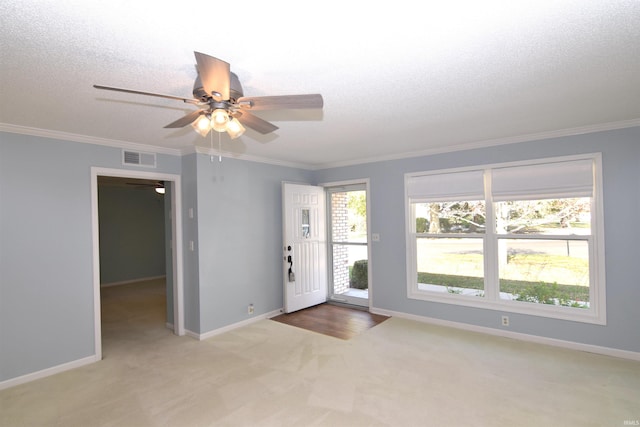 carpeted spare room with ceiling fan, ornamental molding, and a textured ceiling