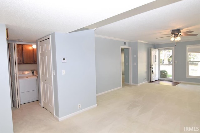 carpeted empty room with independent washer and dryer, a textured ceiling, crown molding, and ceiling fan