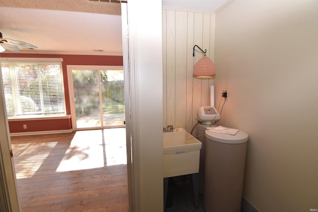 interior space with a textured ceiling, ceiling fan, toilet, hardwood / wood-style flooring, and ornamental molding