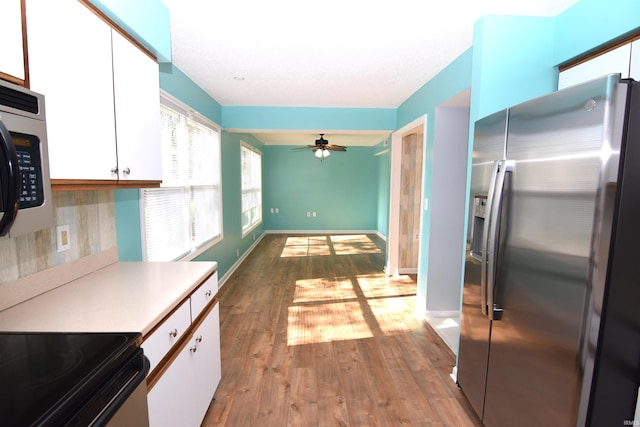 kitchen featuring decorative backsplash, white cabinetry, stainless steel appliances, and light hardwood / wood-style floors