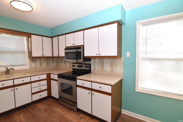 kitchen with appliances with stainless steel finishes, white cabinetry, a textured ceiling, dark wood-type flooring, and sink