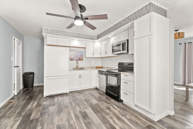 kitchen featuring white fridge, hardwood / wood-style flooring, black electric range oven, and white cabinetry