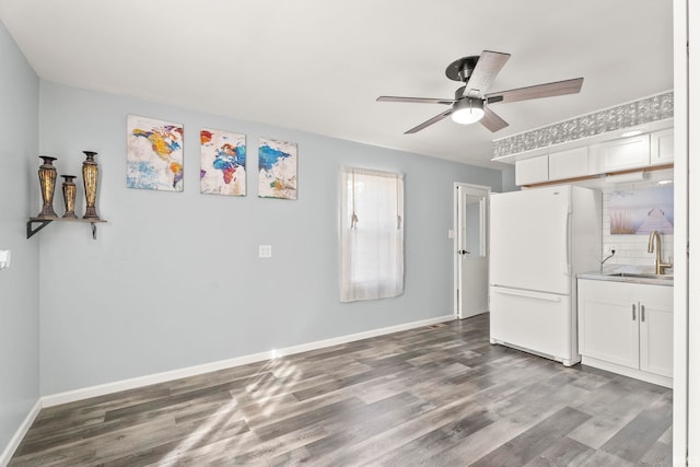 kitchen featuring wood-type flooring, sink, backsplash, white cabinetry, and white refrigerator