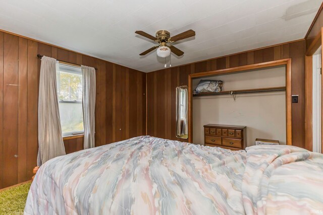 bedroom featuring a closet, wood walls, and ceiling fan