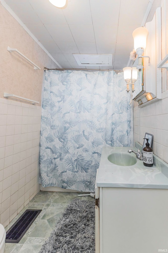 bathroom featuring vanity, toilet, tile walls, and curtained shower