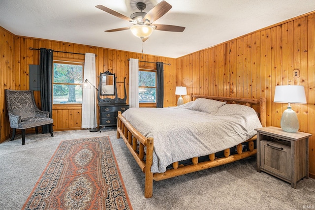 bedroom featuring wood walls, a textured ceiling, carpet, and ceiling fan