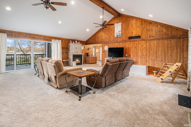 carpeted living room with wood walls, beam ceiling, and ceiling fan