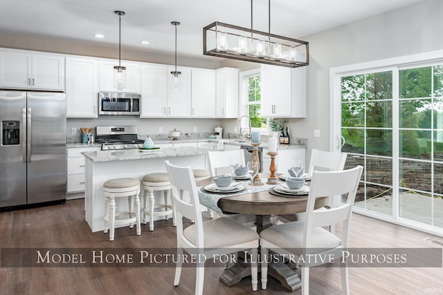 kitchen featuring white cabinetry, stainless steel appliances, a wealth of natural light, and pendant lighting