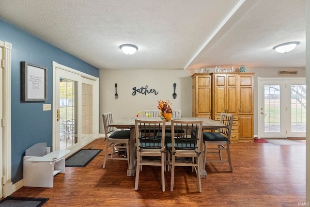 dining room featuring a textured ceiling, plenty of natural light, and dark hardwood / wood-style flooring