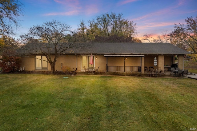 back house at dusk with a lawn