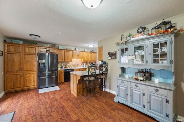 kitchen featuring dishwasher, dark hardwood / wood-style floors, a breakfast bar area, fridge with ice dispenser, and a textured ceiling