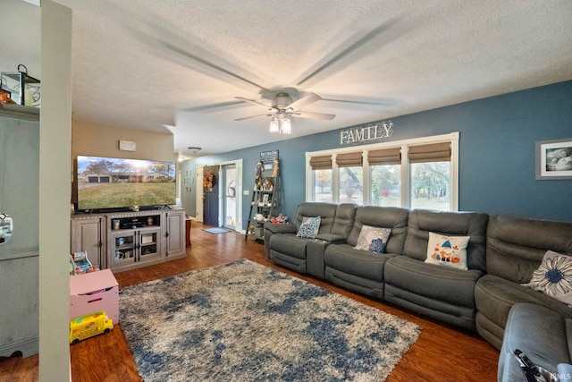 living room with ceiling fan, a textured ceiling, and dark hardwood / wood-style floors