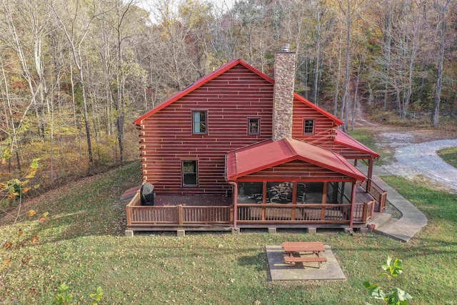 back of property with a wooden deck and a lawn