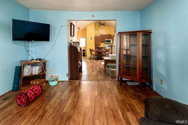 living room featuring a textured ceiling, wood-type flooring, vaulted ceiling, and ceiling fan