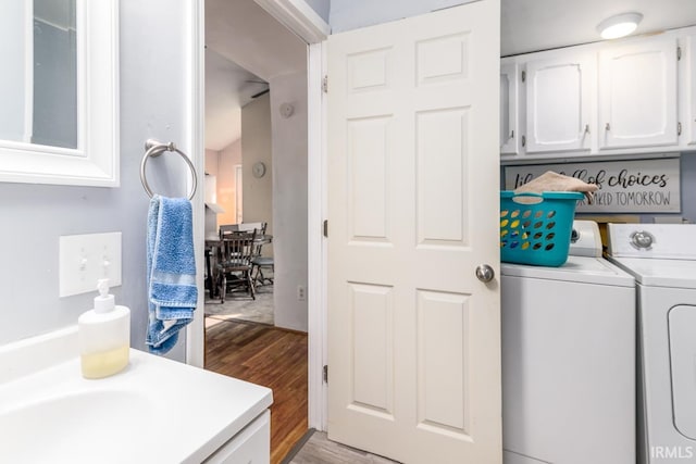 laundry room with hardwood / wood-style flooring, washing machine and dryer, and cabinets