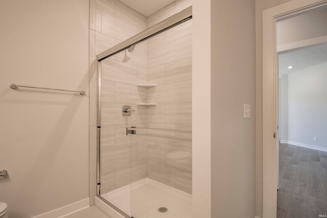 bathroom with a shower with door, toilet, and wood-type flooring