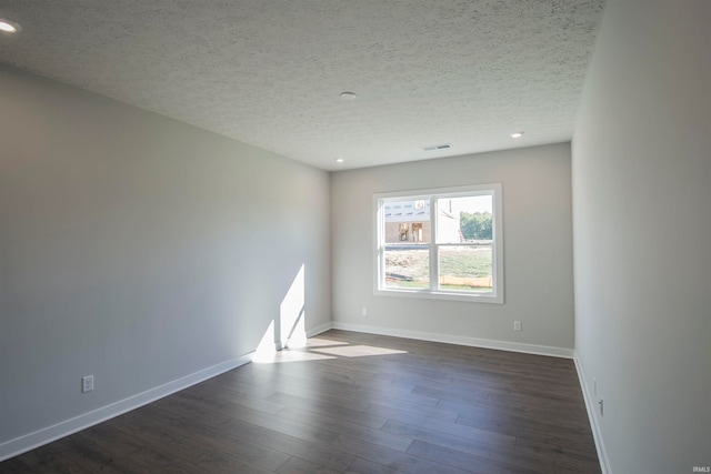 empty room featuring dark wood-type flooring and a textured ceiling