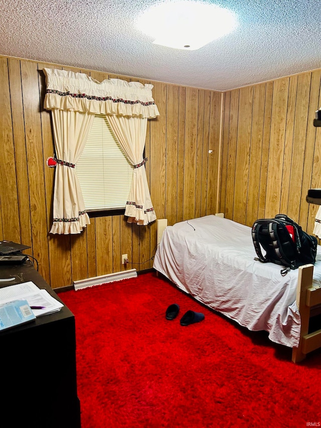 bedroom featuring a textured ceiling, a baseboard heating unit, carpet flooring, and wood walls