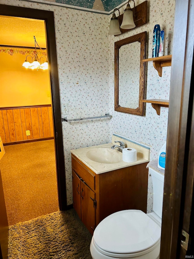 bathroom featuring vanity, toilet, and wood walls