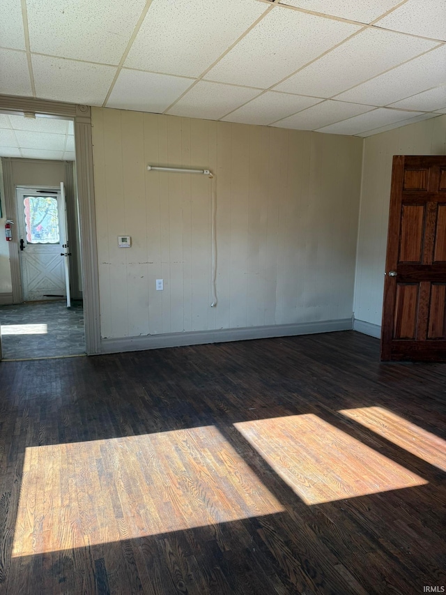 empty room with a drop ceiling and dark hardwood / wood-style flooring