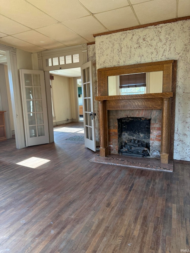 unfurnished living room featuring dark wood-type flooring, french doors, and a drop ceiling