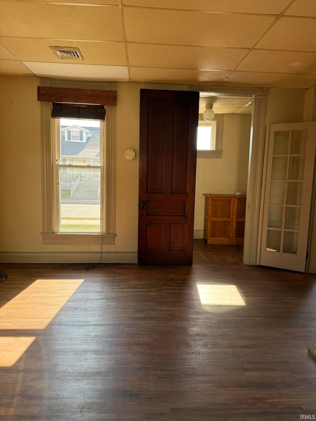 spare room with wood walls, dark hardwood / wood-style flooring, and a drop ceiling