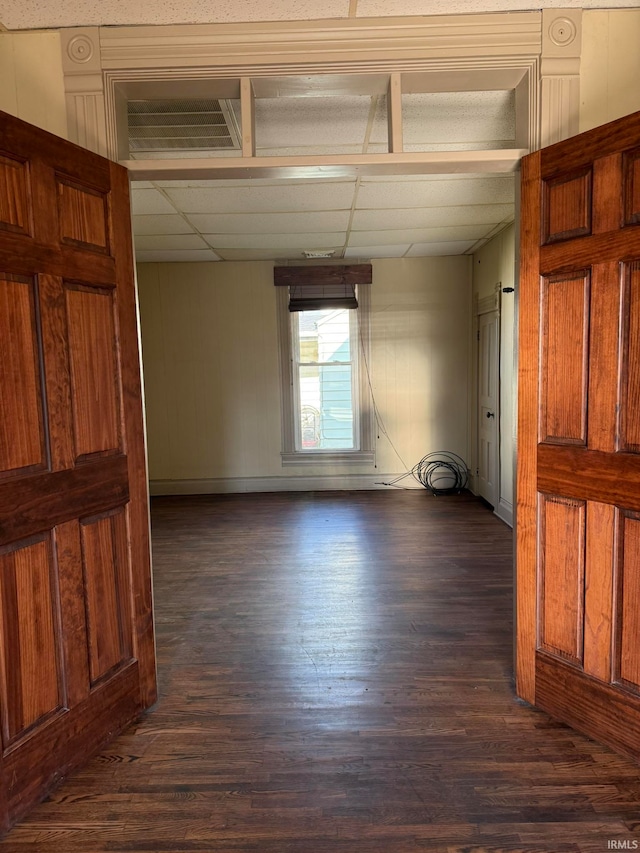 unfurnished room featuring wood walls, a paneled ceiling, and dark hardwood / wood-style flooring