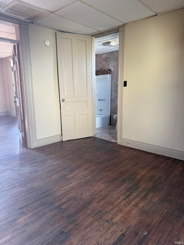 empty room with dark hardwood / wood-style floors and a paneled ceiling