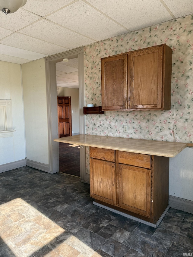 422 E Water St A-B, Unit A-B Portland, IN 47371 - kitchen featuring brown cabinetry, wallpapered walls, light countertops, a drop ceiling, and baseboards
