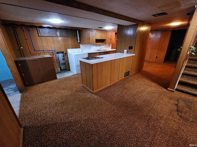 kitchen featuring wooden walls, kitchen peninsula, sink, and washer / clothes dryer