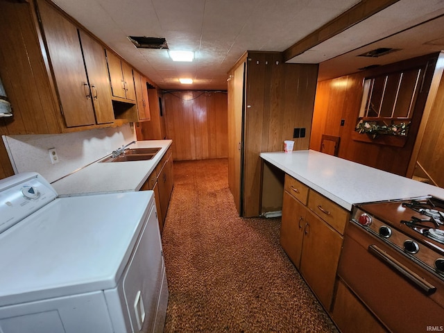 kitchen featuring range, wood walls, sink, and washer / dryer