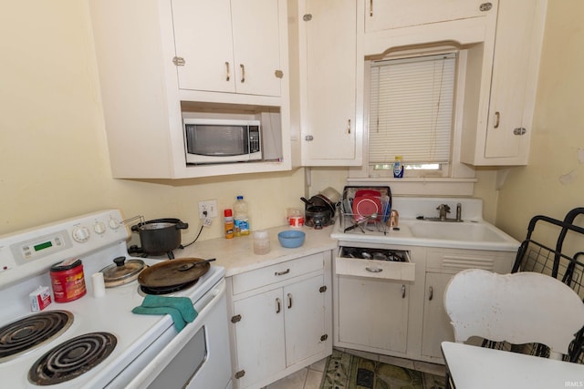 kitchen featuring sink, white cabinets, tile patterned flooring, and electric stove