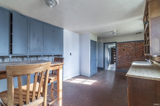 8126 Coldwater Rd, Fort Wayne, IN 46825 - kitchen with brick patterned flooring, blue cabinets, baseboards, a sink, and light countertops