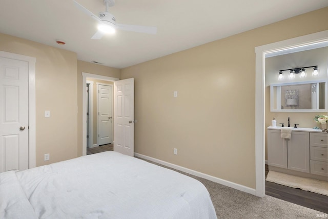 bedroom featuring ceiling fan, sink, ensuite bath, and dark hardwood / wood-style flooring