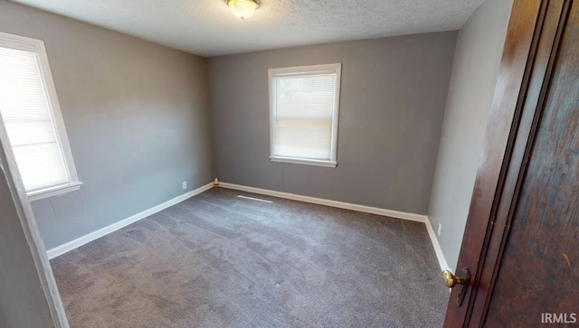 carpeted empty room featuring a textured ceiling