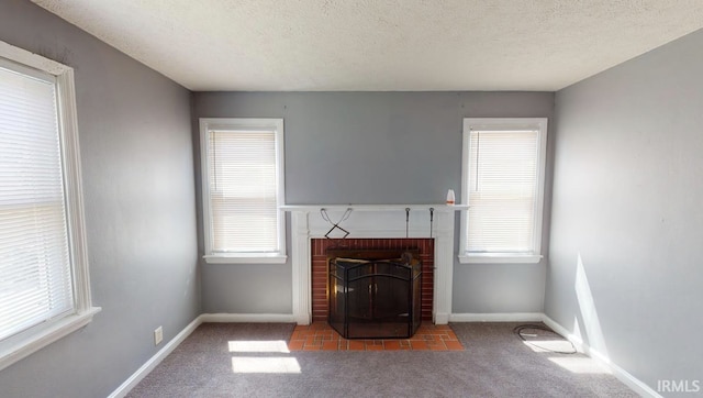 unfurnished living room featuring a textured ceiling, a healthy amount of sunlight, carpet, and a brick fireplace