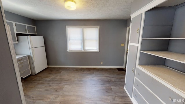 kitchen featuring hardwood / wood-style flooring, a textured ceiling, and white refrigerator