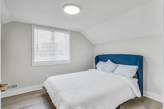 bedroom featuring hardwood / wood-style floors and vaulted ceiling