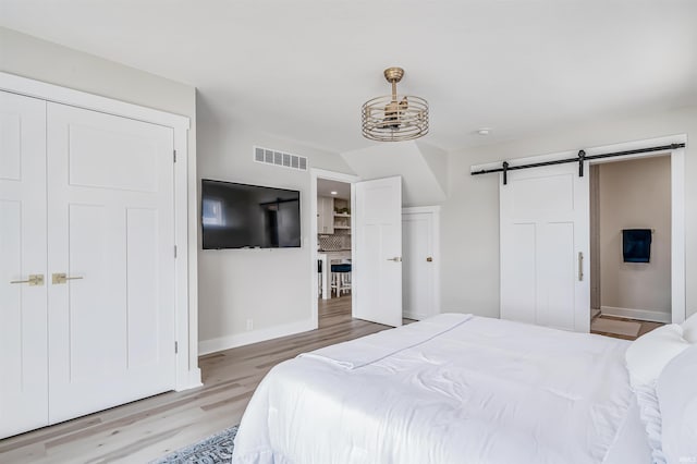 bedroom featuring a closet, ensuite bathroom, a barn door, and hardwood / wood-style floors