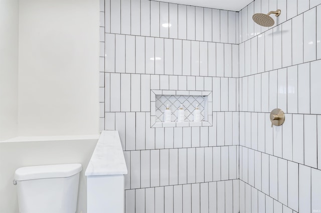 bathroom featuring a tile shower, toilet, and vanity