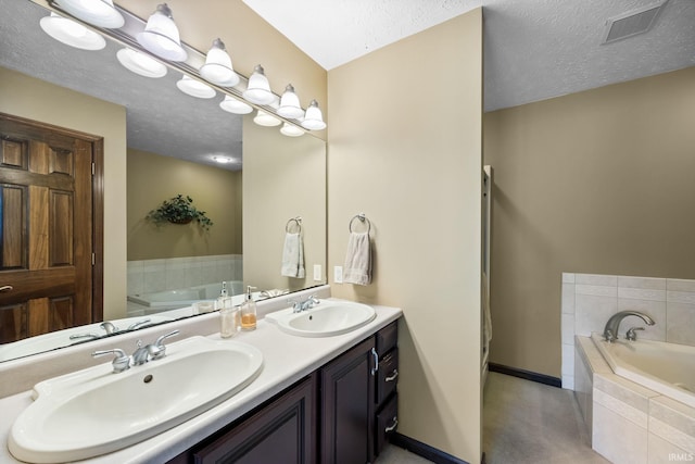 bathroom featuring vanity, a relaxing tiled tub, and a textured ceiling