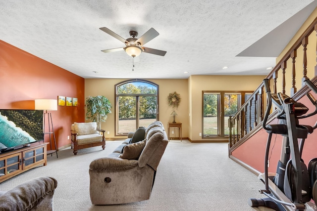 living room featuring light carpet, a textured ceiling, and ceiling fan