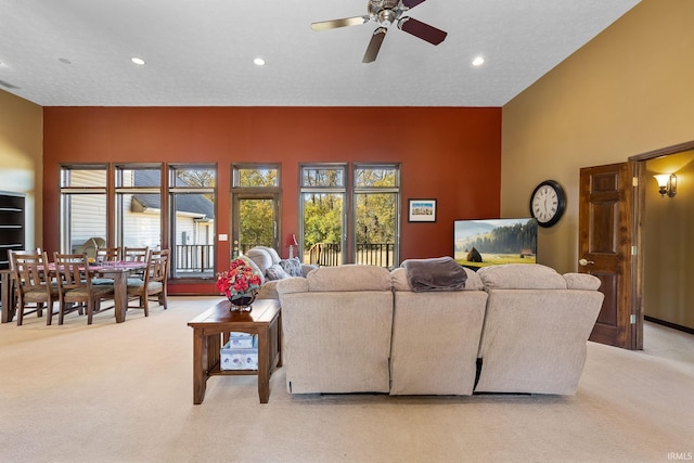 carpeted living room with ceiling fan and a textured ceiling